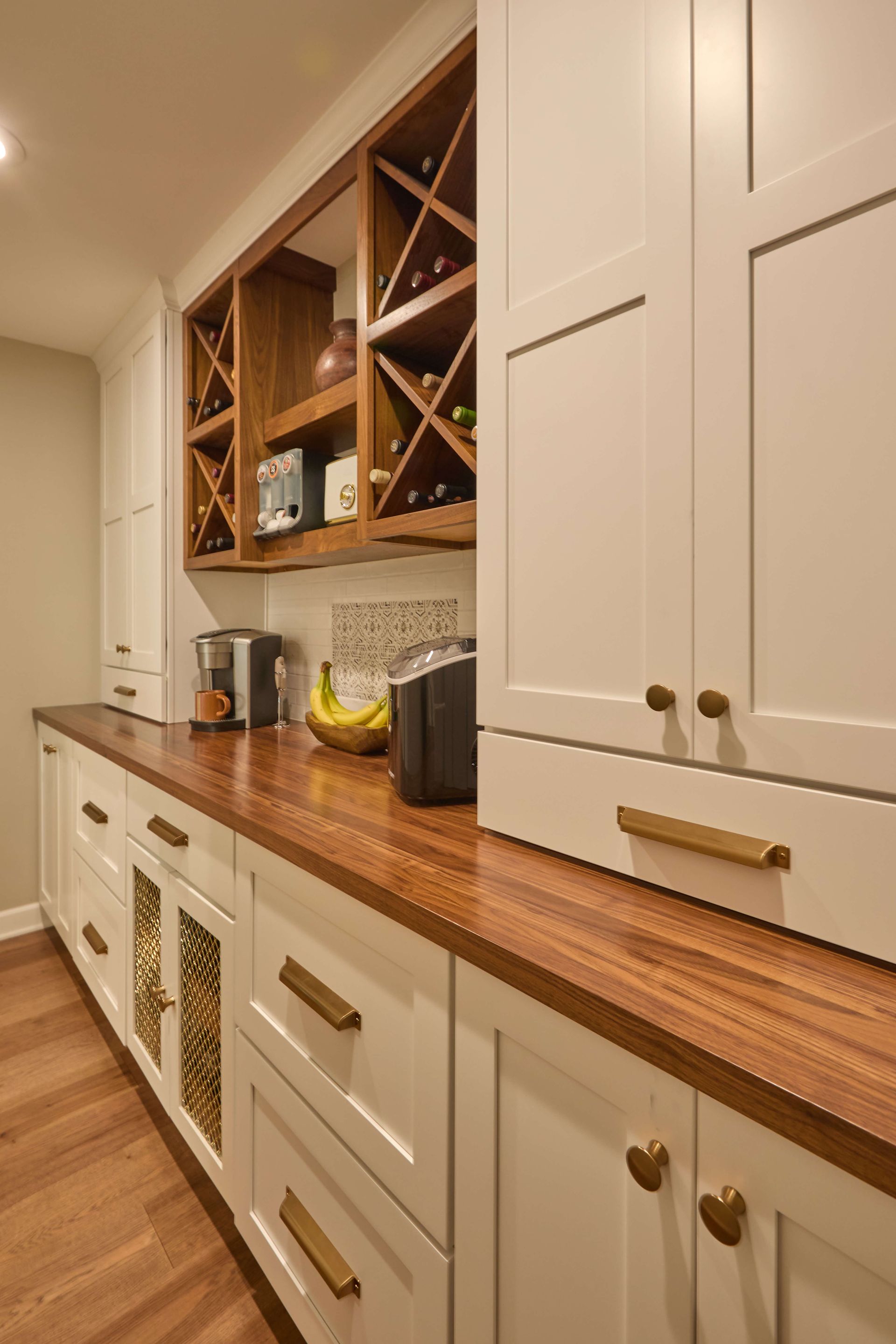 Modern kitchen with white cabinets, wood countertop, and built-in wine rack along the wall