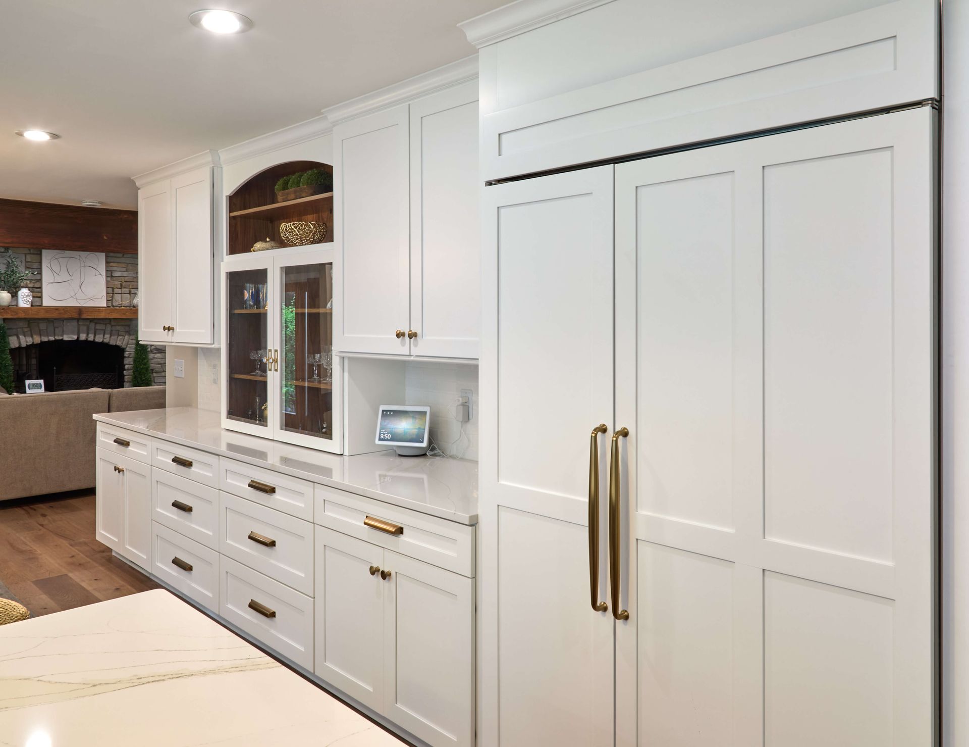 White kitchen with built-in cabinets, double pantry doors, and gold handles