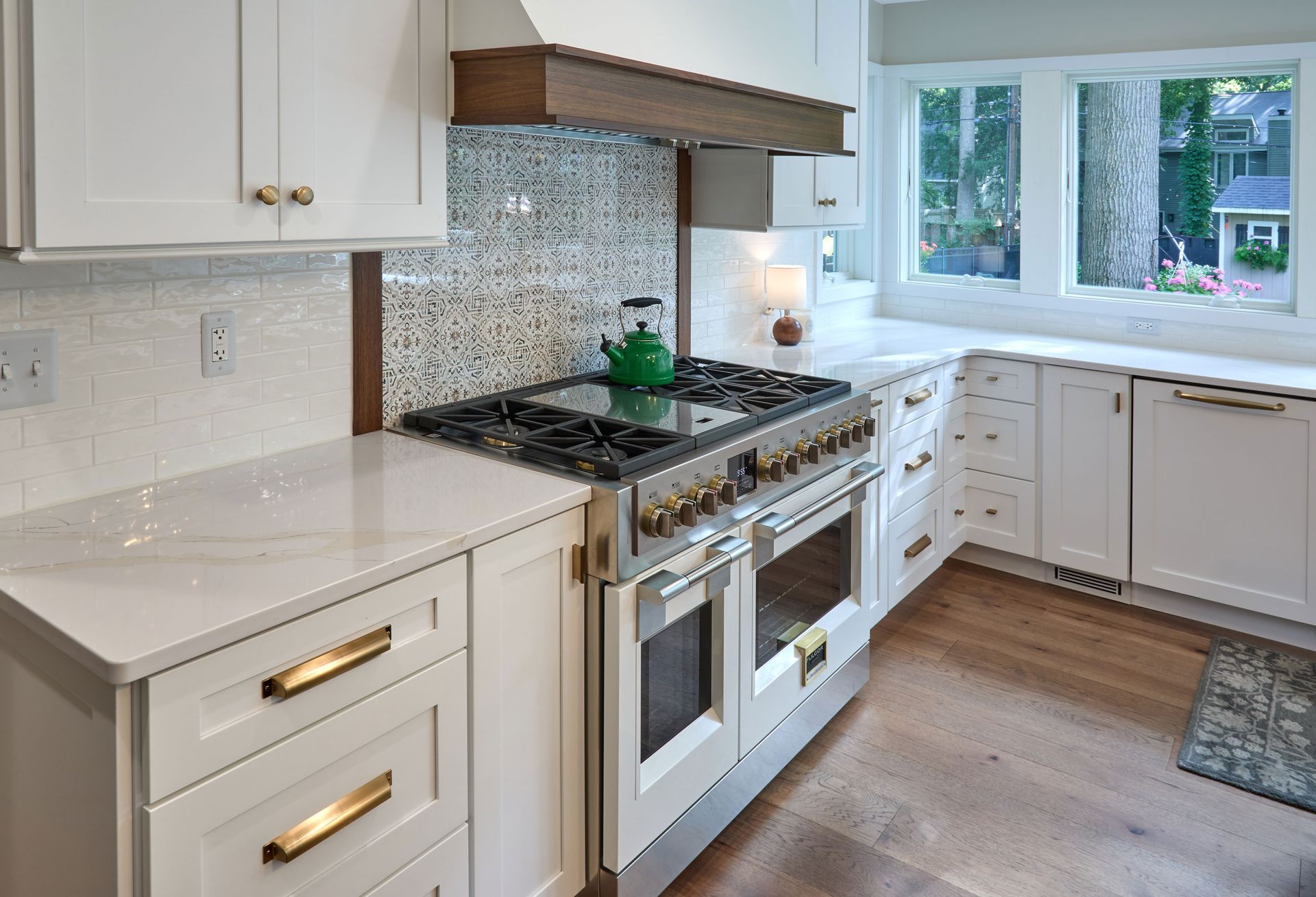 Bright white kitchen with gas stove, mosaic backsplash, and sunlit window above the counter