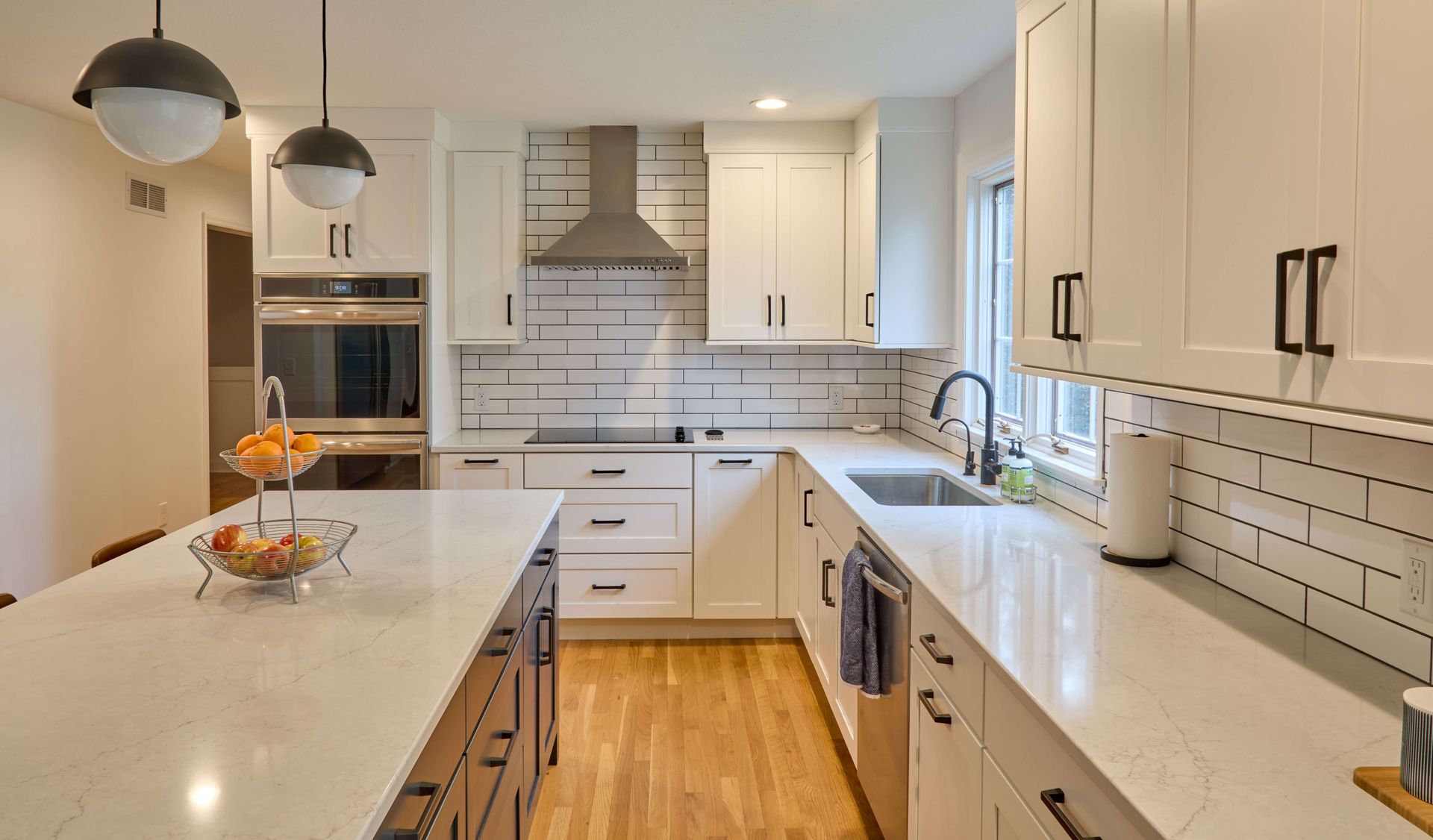 Modern kitchen with white cabinets, quartz countertops, and stainless steel appliances.