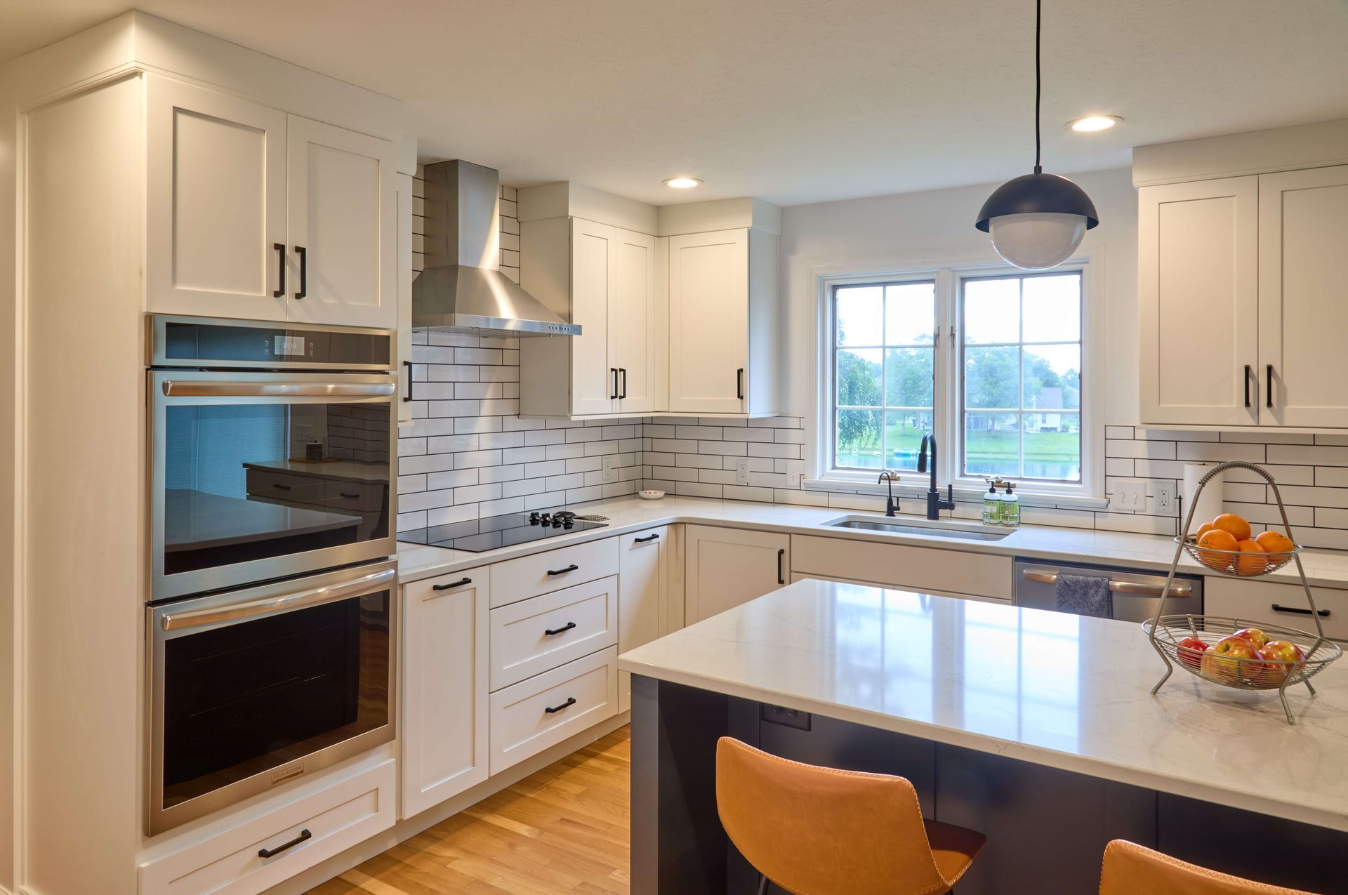 Bright modern kitchen with white cabinets, stainless appliances, island, and window over the sink