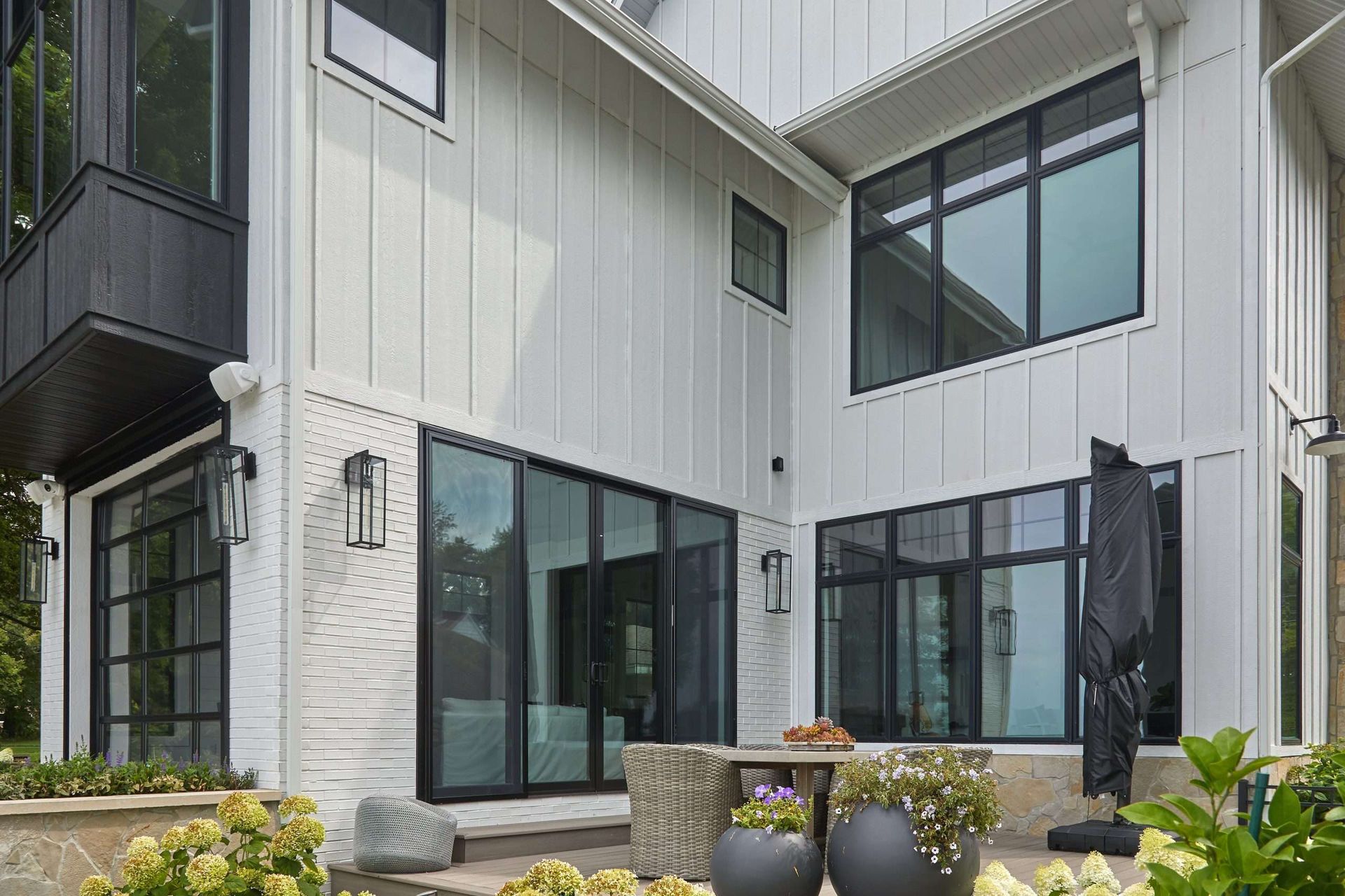 Modern apartment building exterior with black-framed windows, white siding, and potted plants