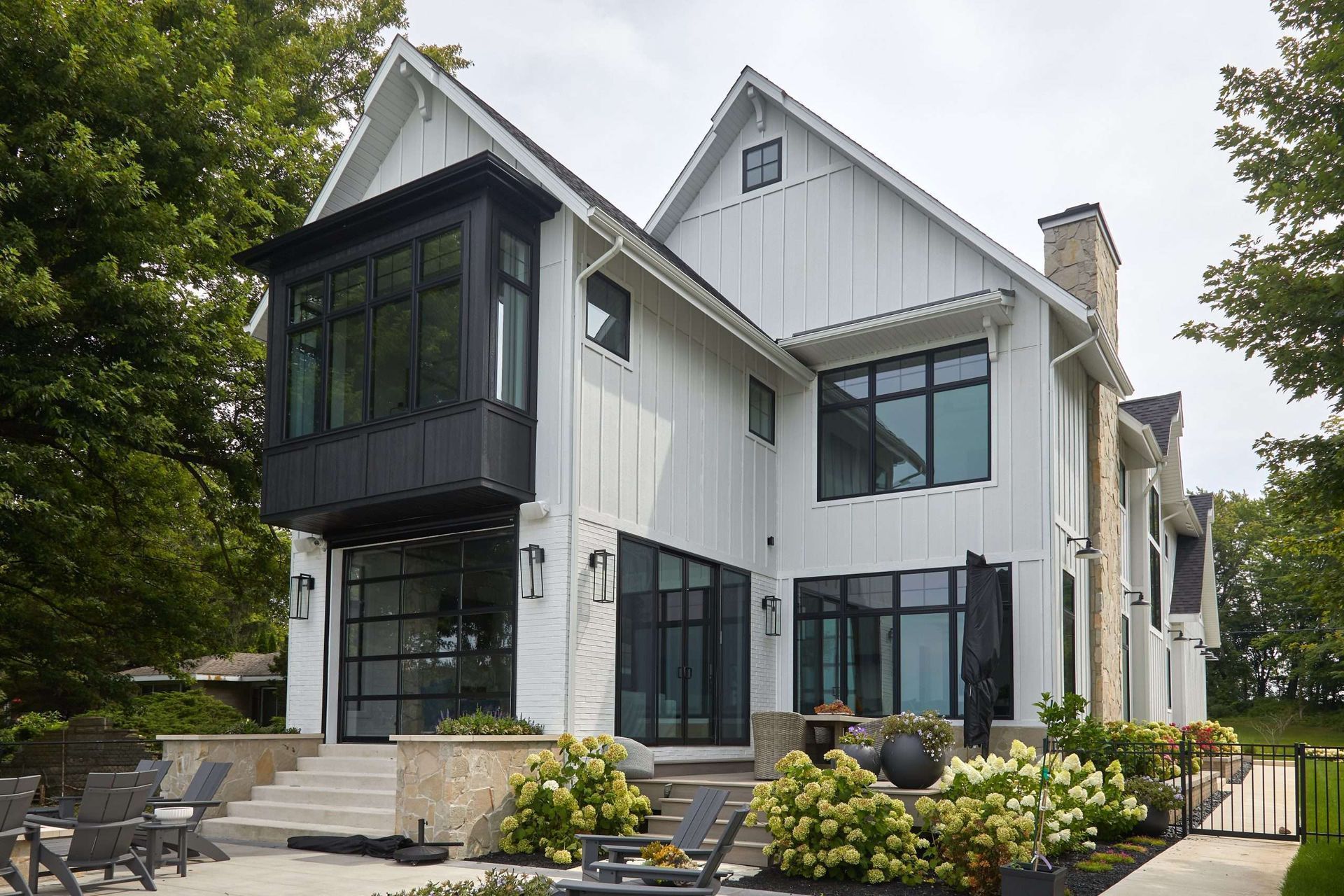 Modern white two-story house with black accents, large windows, and a landscaped front yard