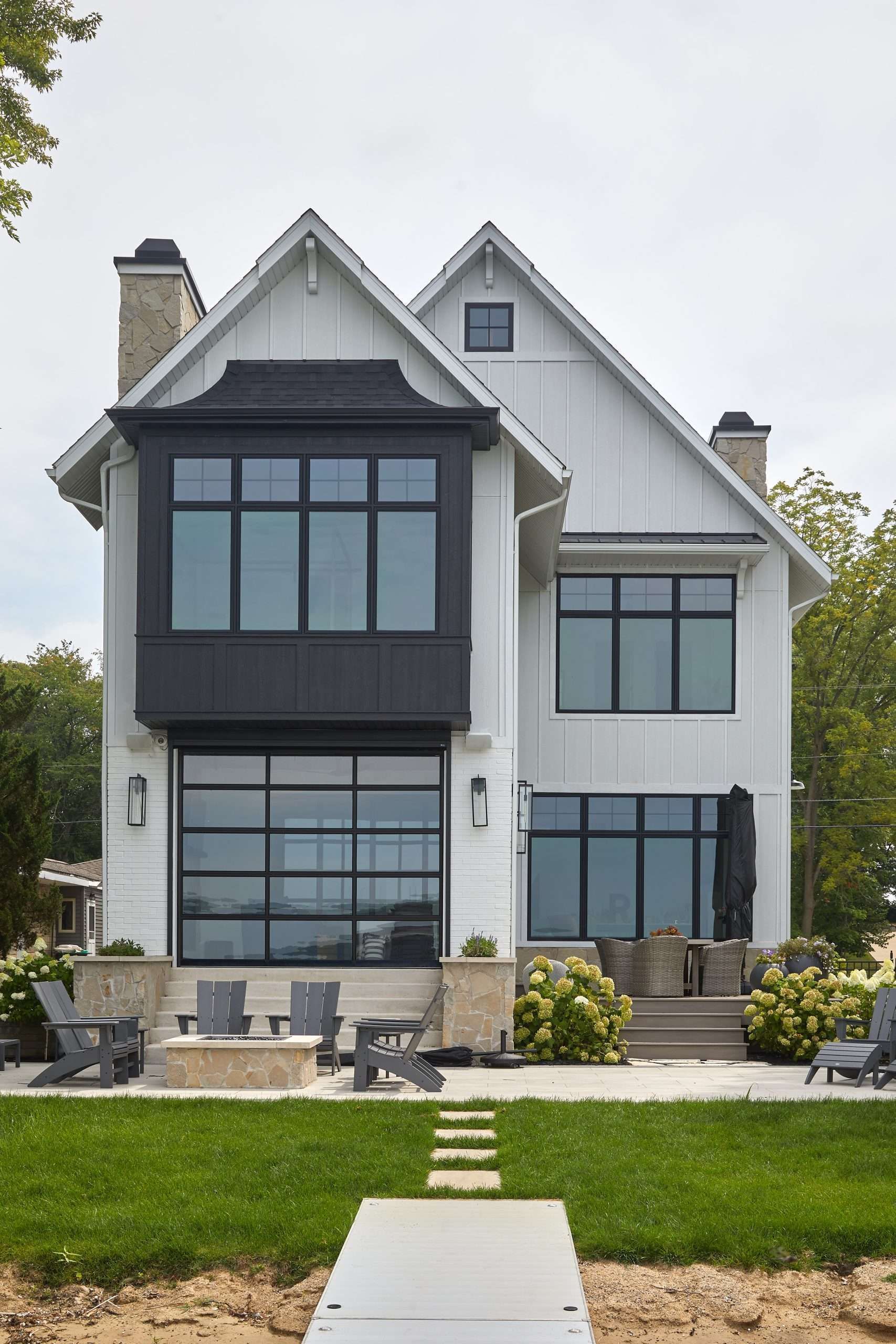 A white house with black windows and a dock in front of it