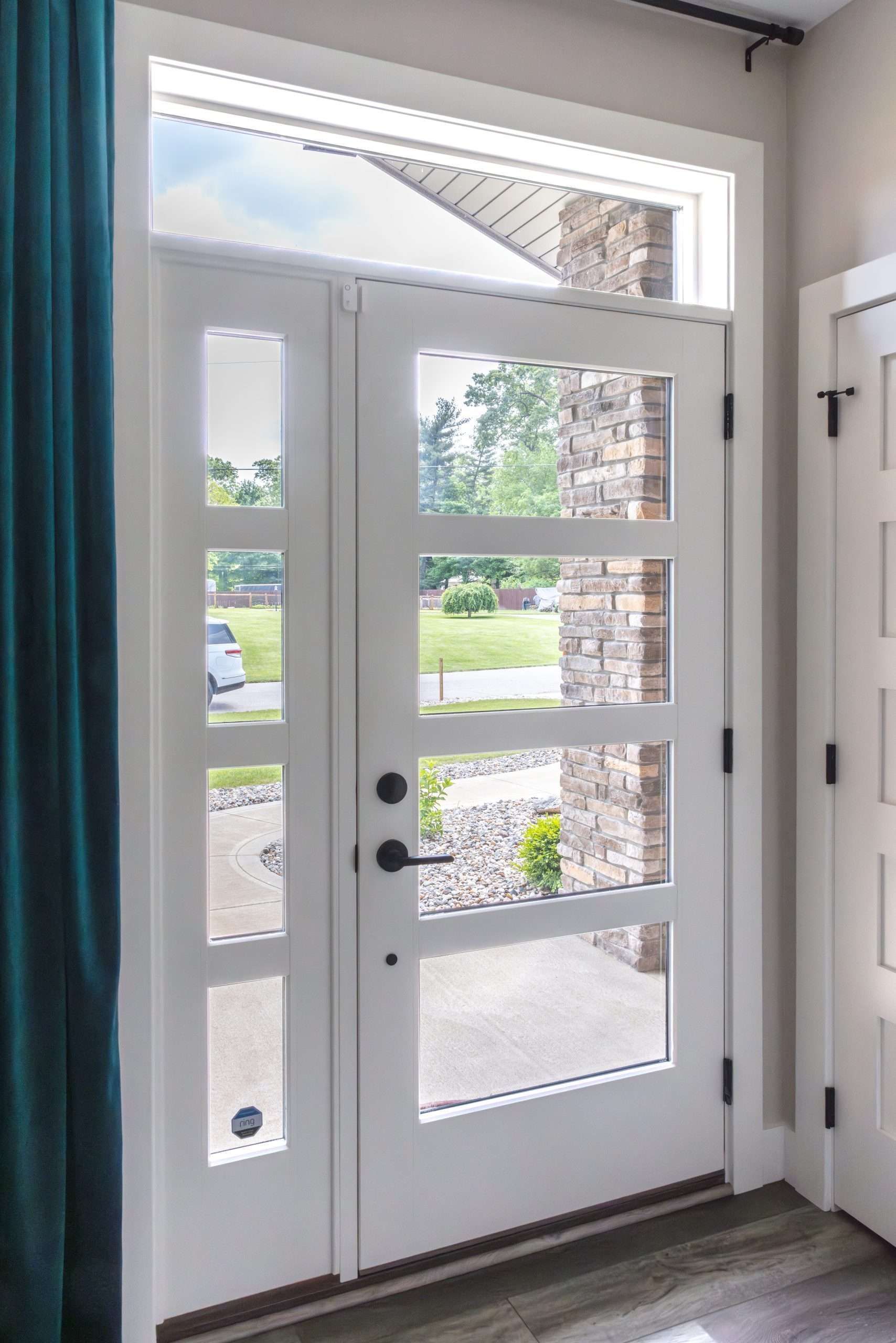 Front entry door with white frame and glass panels, showing a bright outdoor view.