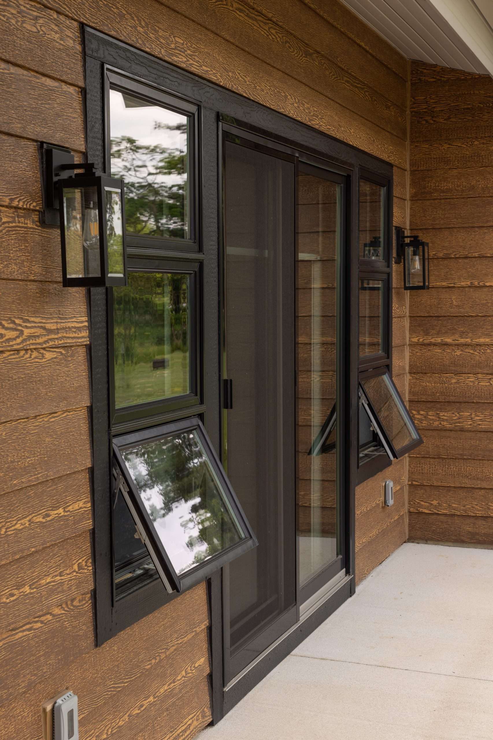 Front entrance with black-framed glass doors and windows on a wood-paneled building porch.
