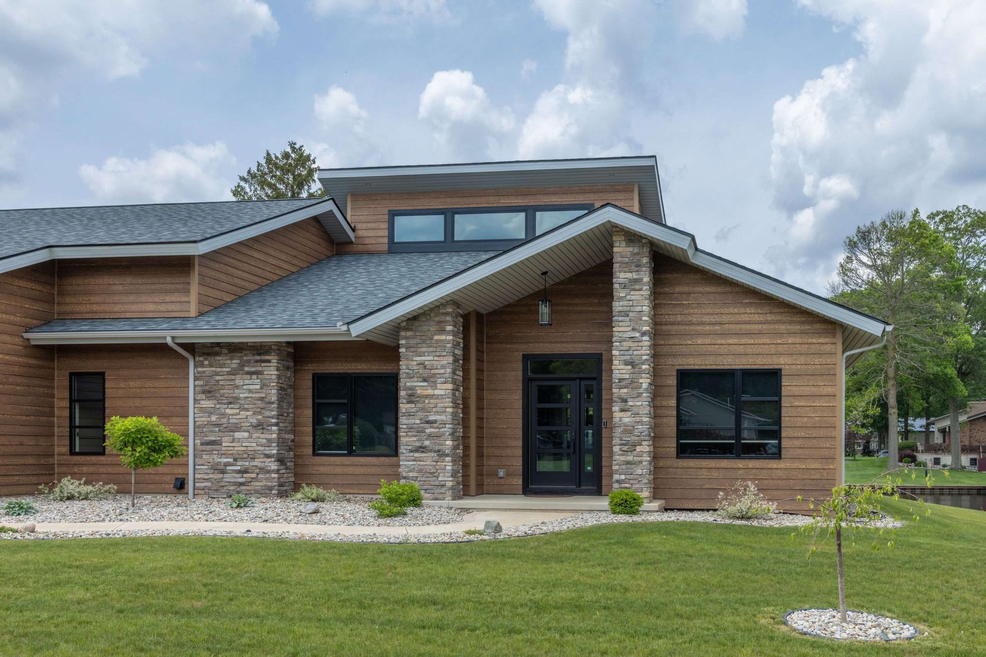 Single-story brick house with gray roof and front lawn under a cloudy sky