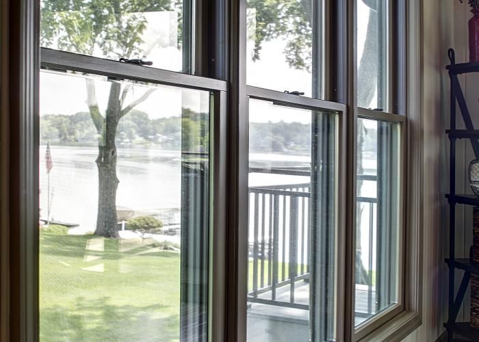 Living room with open sliding glass doors overlooking a grassy yard and lakeview from a balcony
