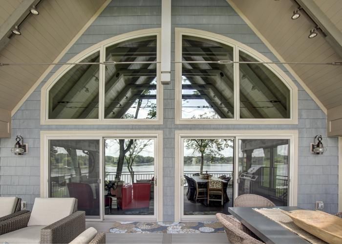 Patio-facing glass doors and arched windows on a beige house exterior, with outdoor seating in front