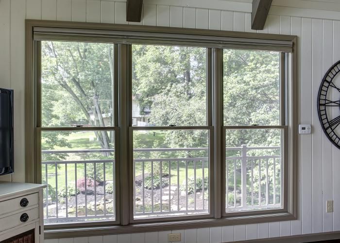 Large window and glass door opening to a green backyard, framed by white paneling and wood trim.