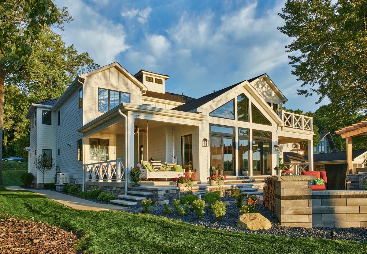 Modern house with large windows, front porch, and landscaped yard in daylight