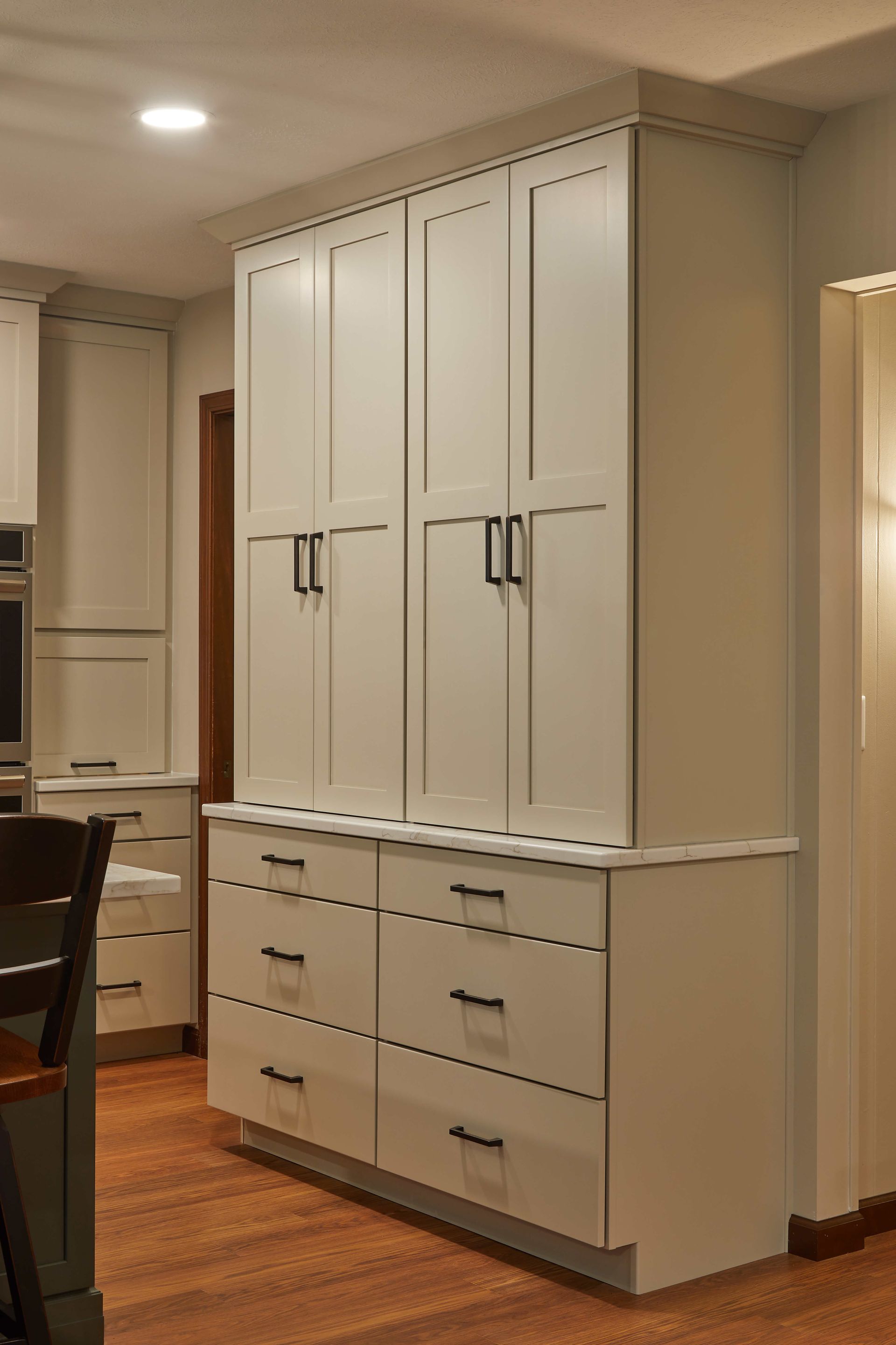 Built-in white storage cabinets with drawers and wardrobe doors in a dining room or hallway