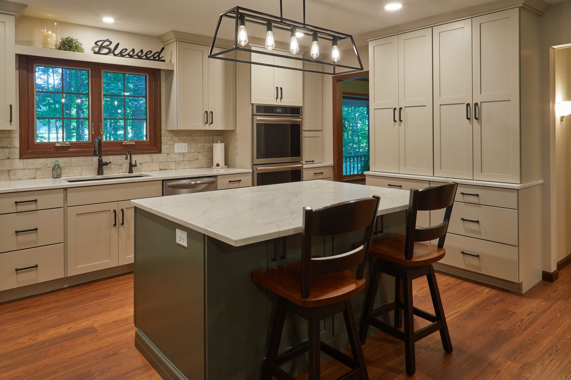 Bright modern kitchen with white cabinets, island, pendant lights, and wood floors