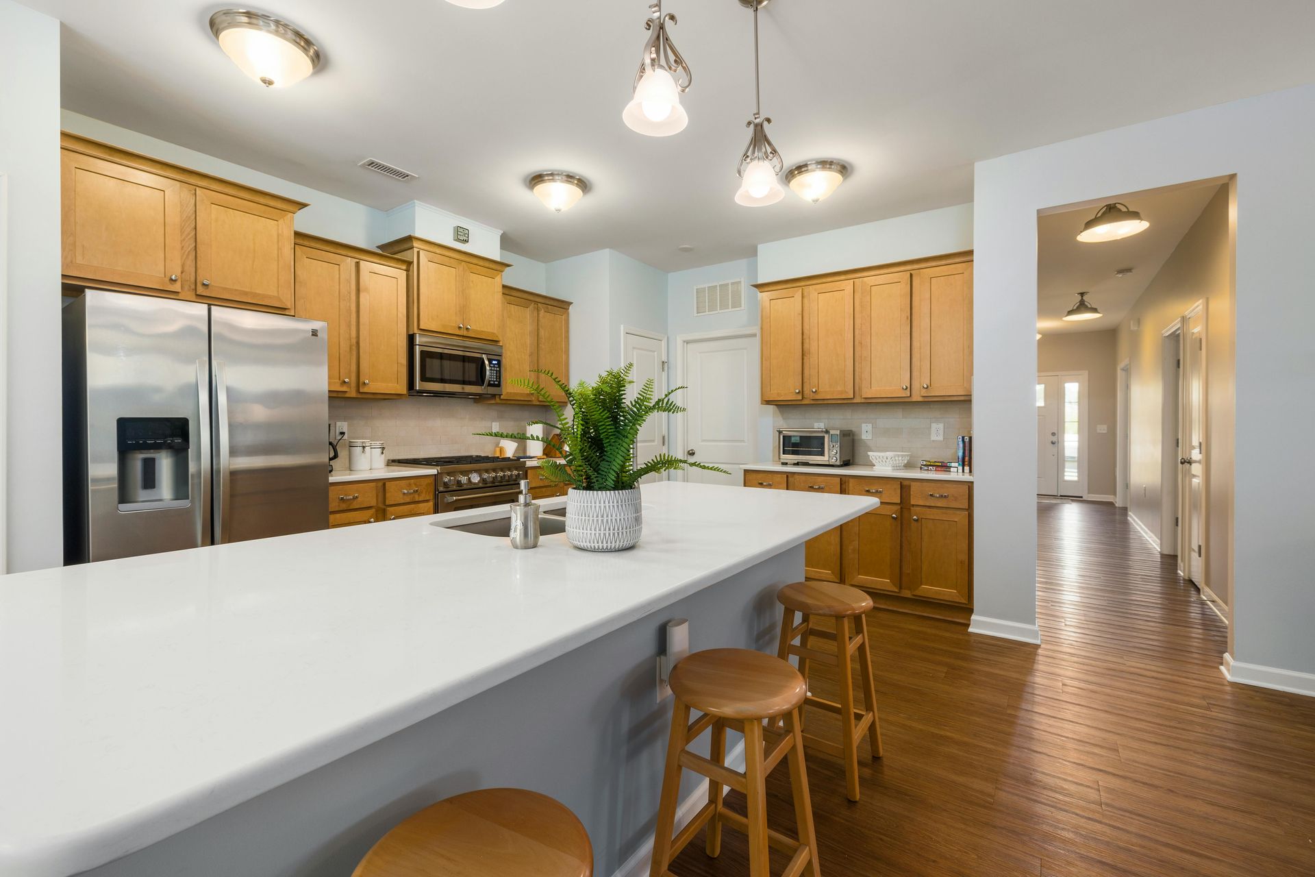Bright kitchen with white island, stainless appliances, light wood cabinets, and hardwood floors