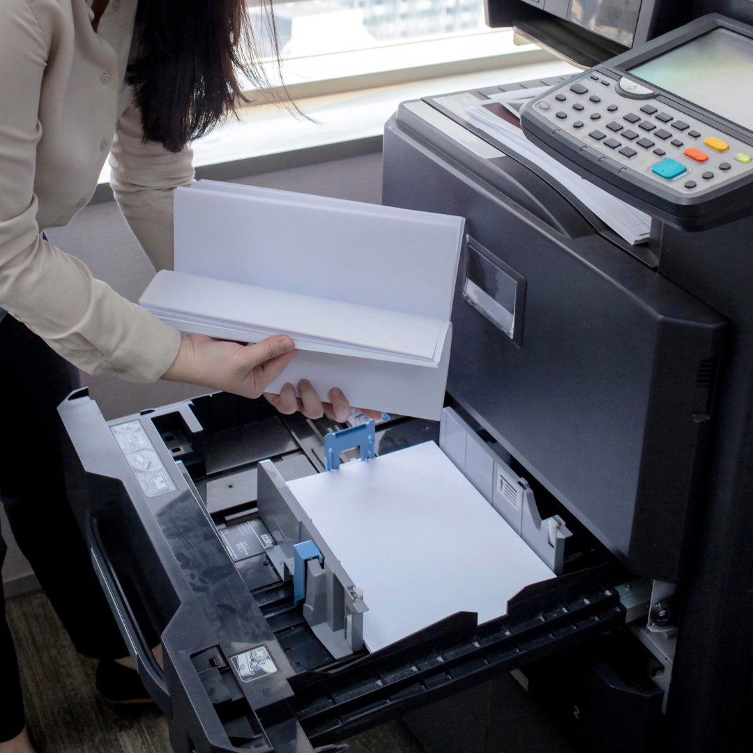 A woman is taking a piece of paper out of a printer