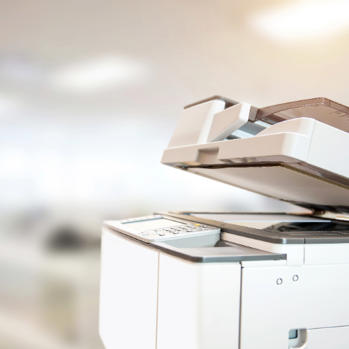 A white printer is sitting in a room with the lid open.