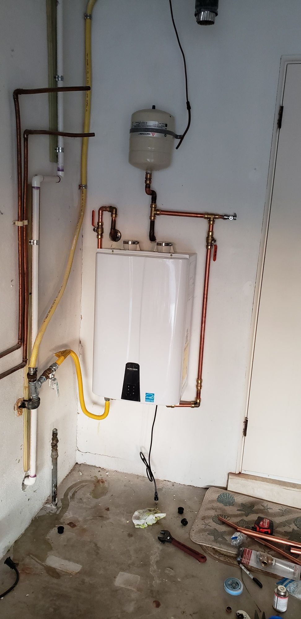 A room with a boiler and pipes on the wall.