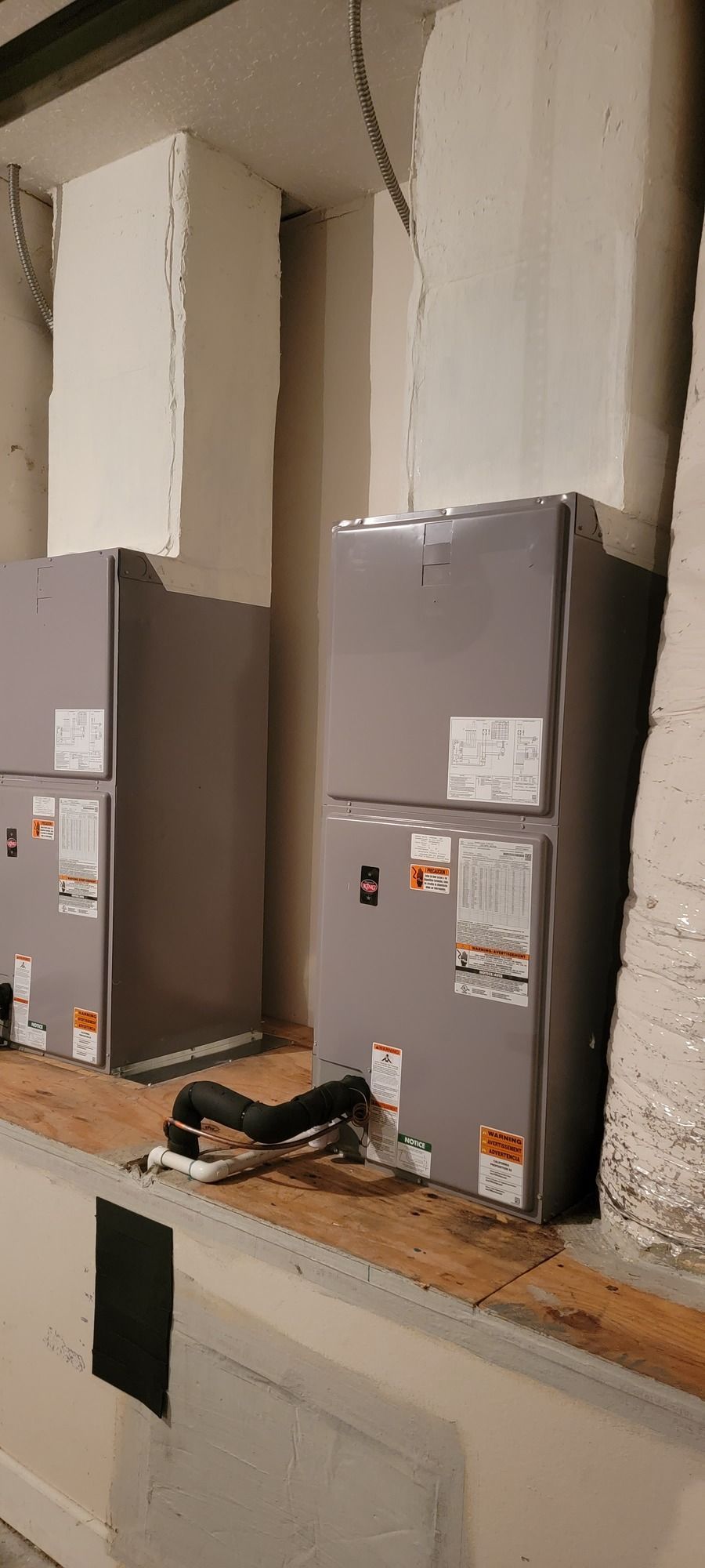 Two air conditioners are sitting on top of a wooden table in a room.