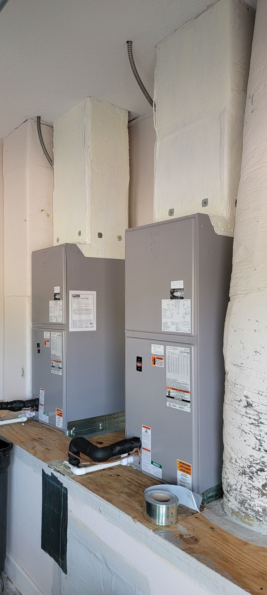 Two air conditioners are sitting next to each other in a room.