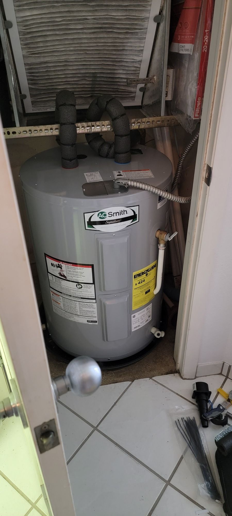 A water heater is sitting in a closet next to a door.