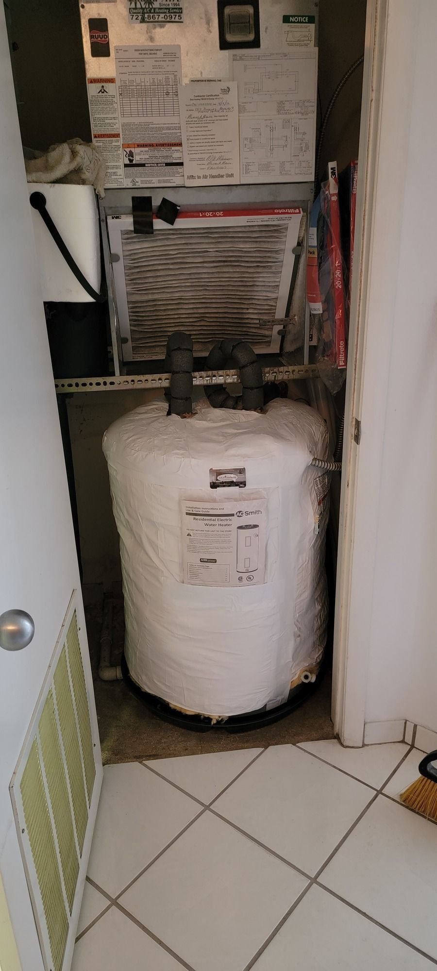A water heater is sitting in a closet next to a door.