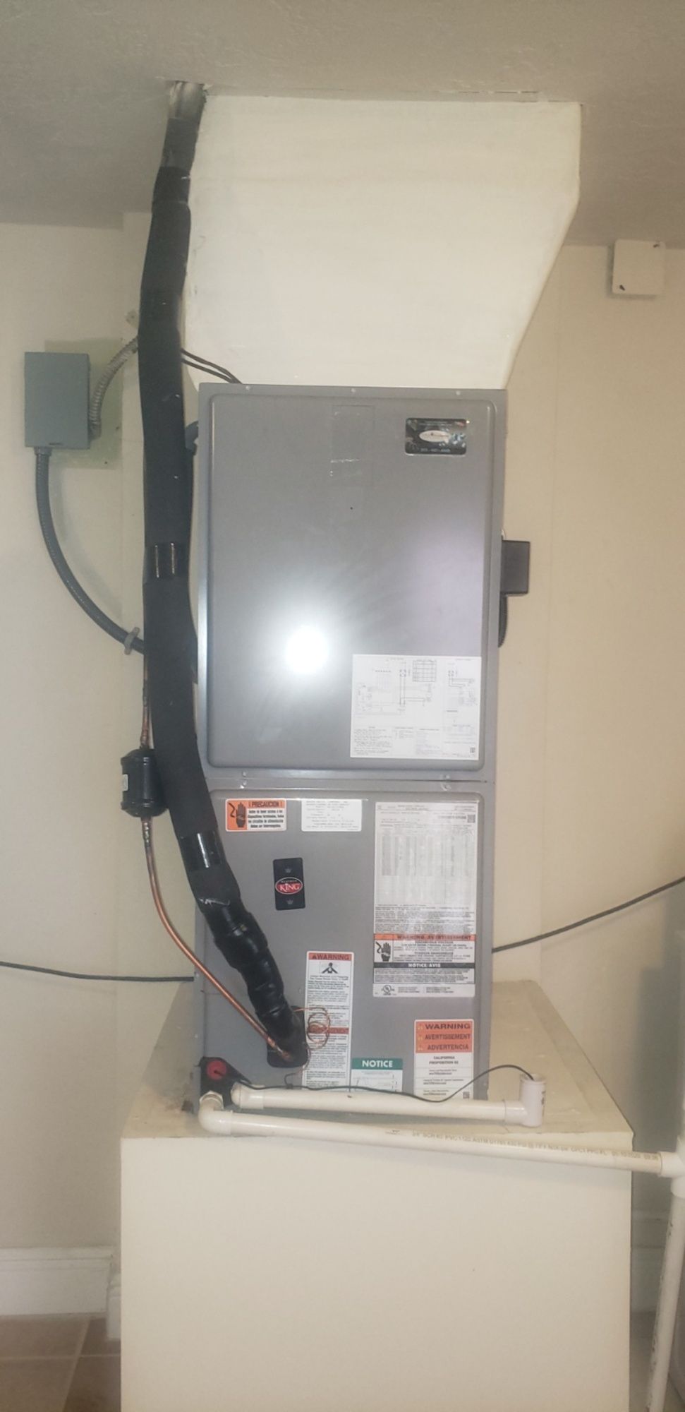 A gray air conditioner is sitting on top of a white table in a room.