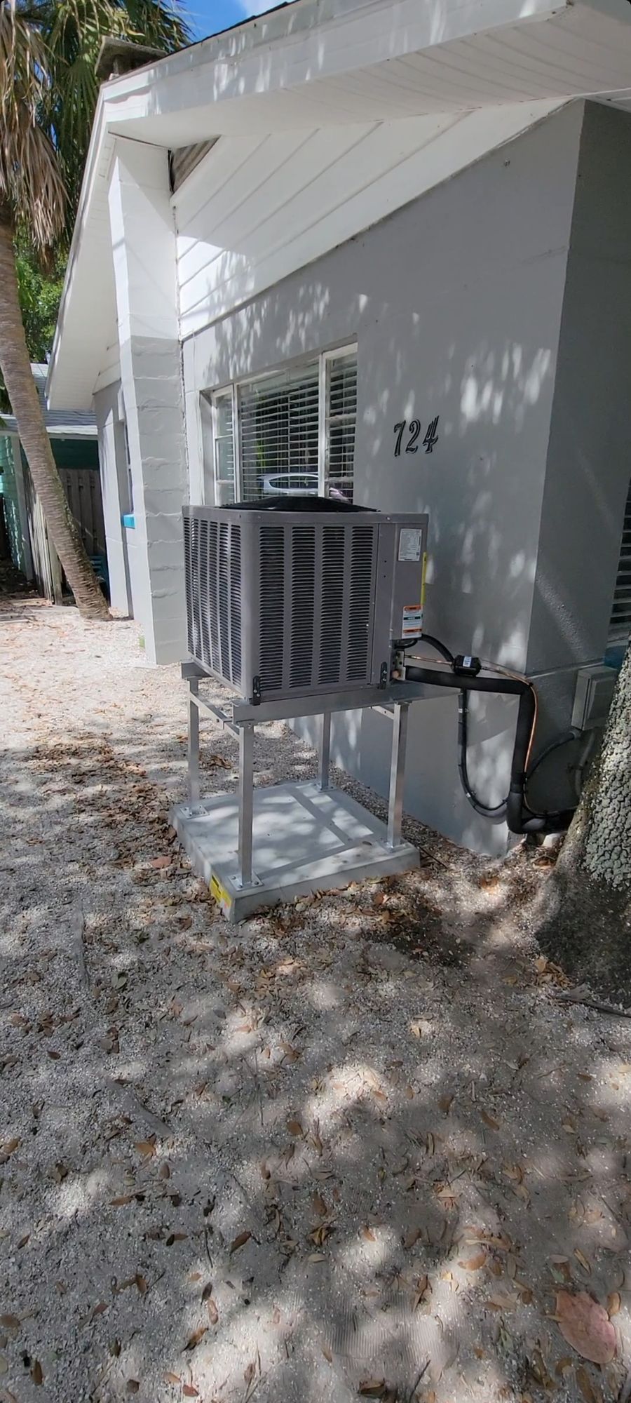 A large air conditioner is sitting outside of a white house.