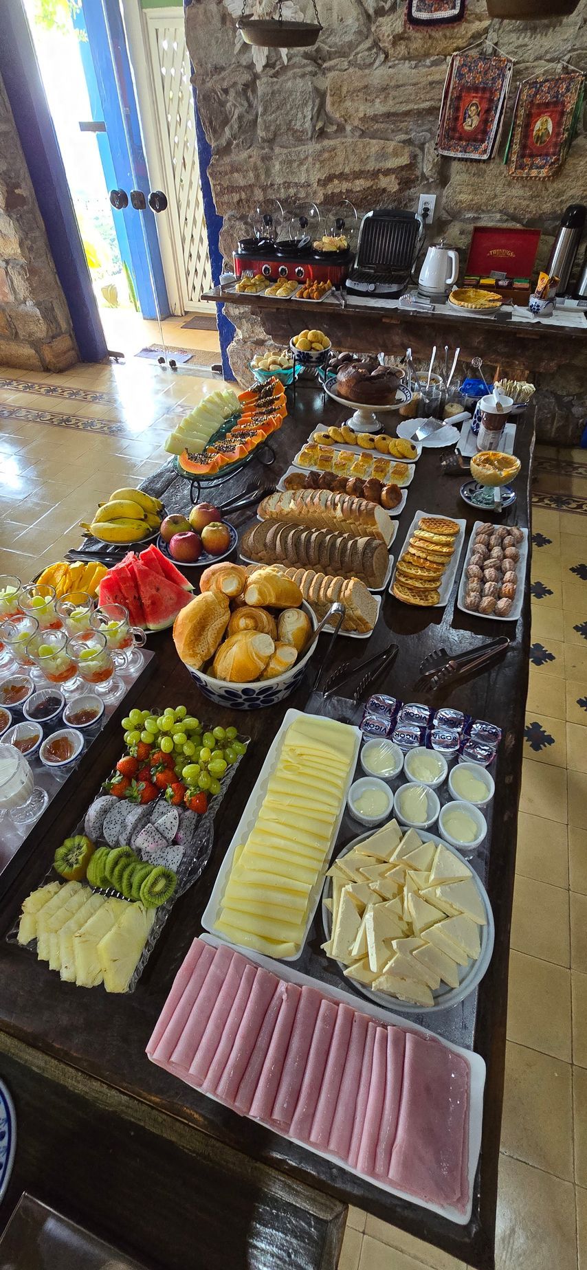 Mesa com uma variedade de doces, frutas e guloseimas dispostas em um colorido bufê interno.