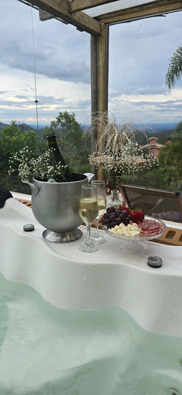 Elegante mesa posta ao ar livre com flores, frutas e uma toalha de mesa verde-menta com vista para uma paisagem deslumbrante.