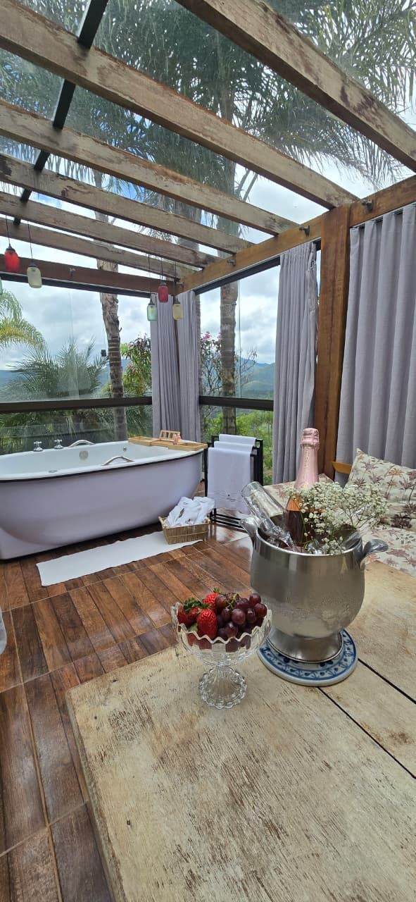 Spa ao ar livre com pérgola de madeira, banheira de hidromassagem branca e vasos de flores em um deck rústico.