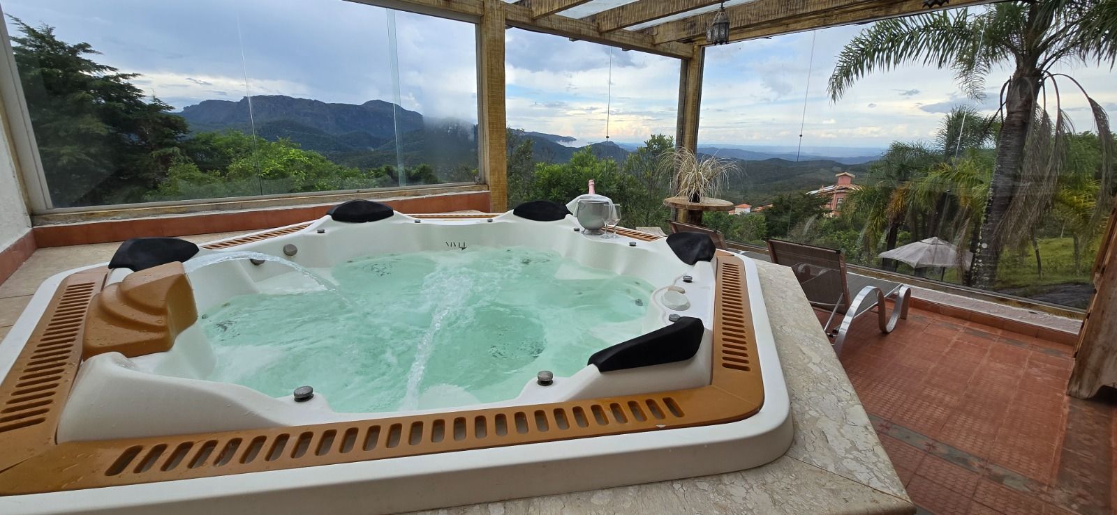 Massagista realizando uma massagem nas costas com velas e pedras de spa em uma sala de spa aquecida.
