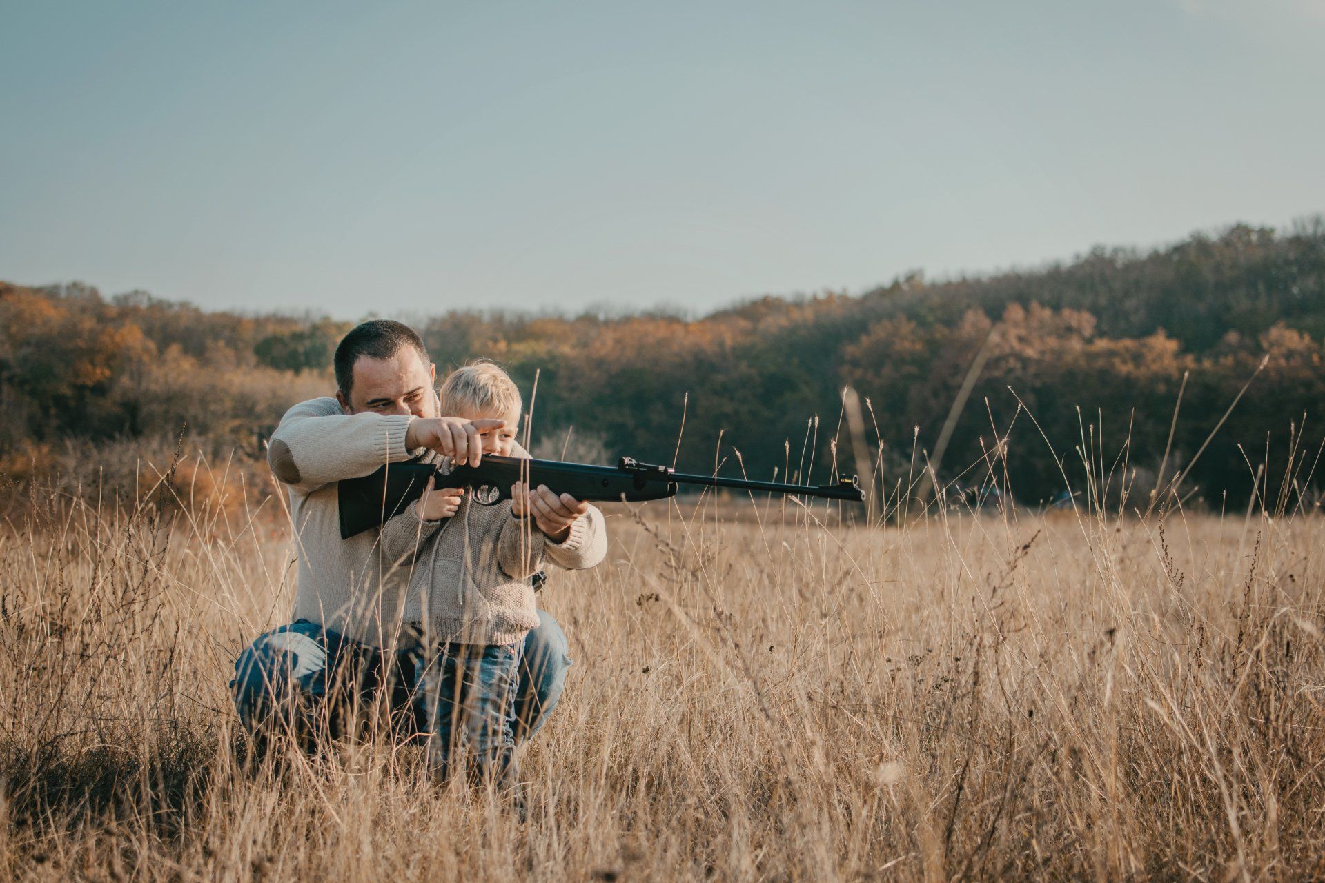 father teaching son to safely use a rifle