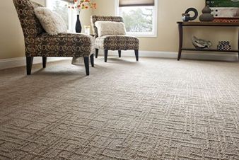 Beige patterned carpet in a living room, with two patterned armchairs, and a side table.