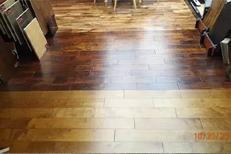 Three wood flooring samples: light, medium, and dark brown, arranged side by side.