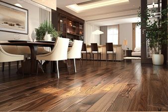 Wooden floor in a dining area with a table and chairs, and a view into a living space.