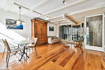 Living room with hardwood floors, dining table, antique cabinet, sofa, and sliding glass doors.