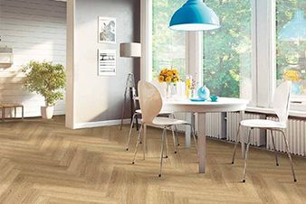 Dining room with light-colored herringbone patterned floor, round table, chairs, and large window with view.