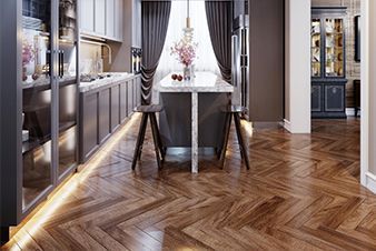 Elegant kitchen with wood herringbone floor, dark cabinets, island with stools, and large window.