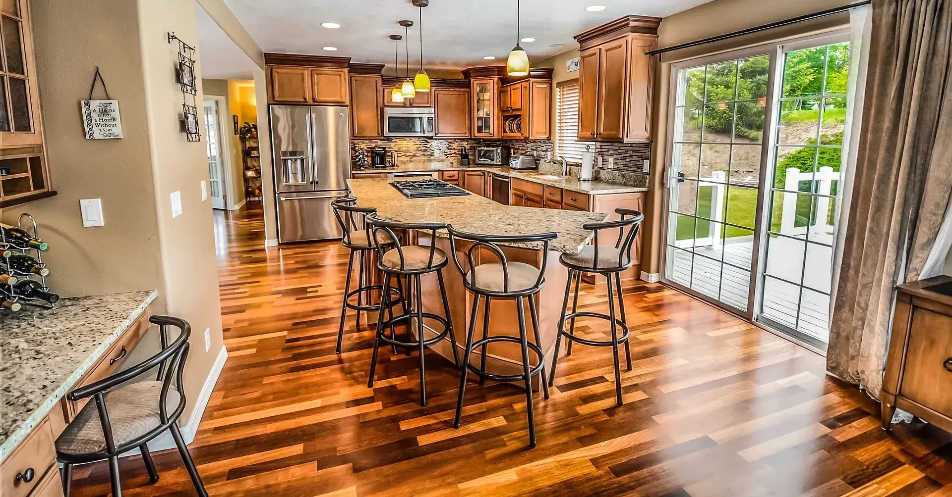 Spacious kitchen with wood cabinets, island with stools, and sliding glass doors to a backyard.