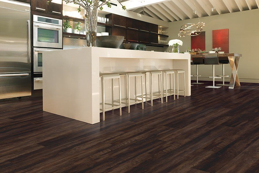 Kitchen with dark wood flooring, a white island with stools, and stainless steel appliances.