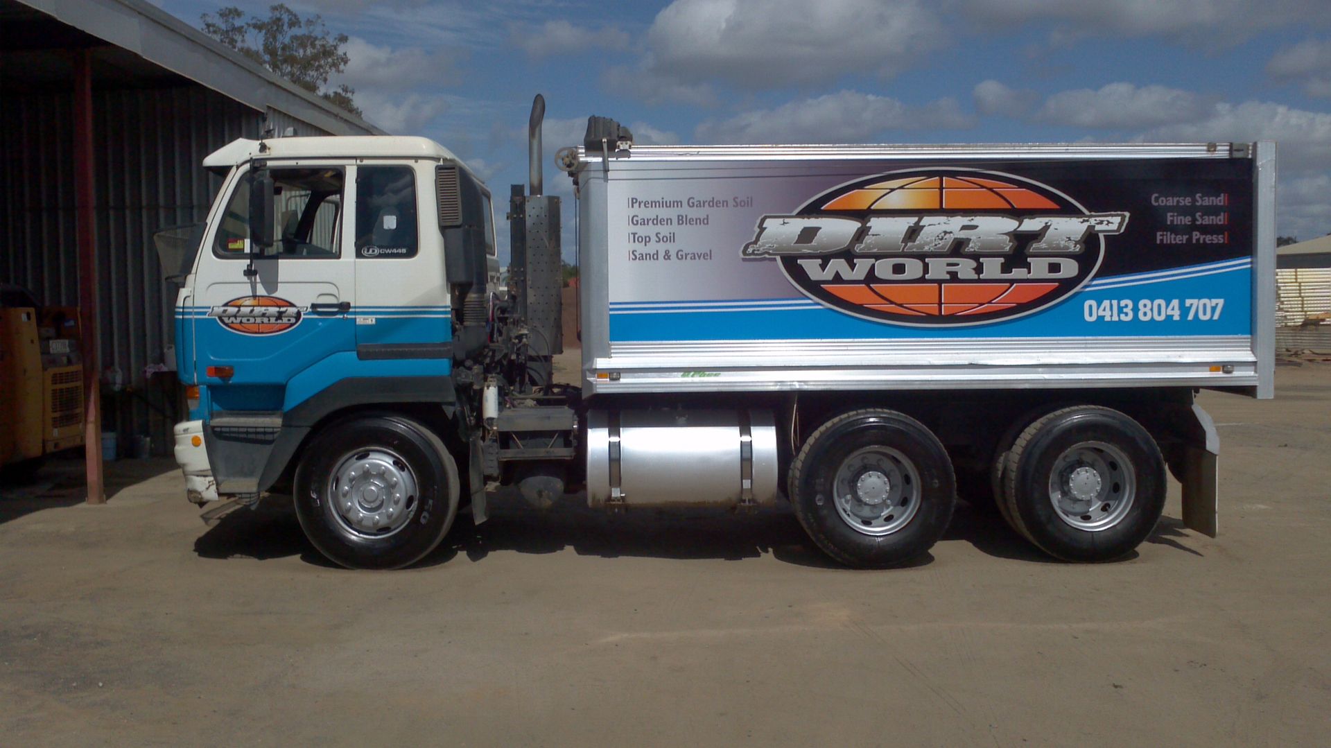 Blue and white truck parked outdoors with a large logo on the side