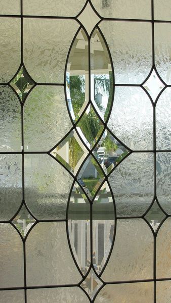Finestra decorativa con vetri a piombo, caratterizzata da un disegno ovale verticale centrale con pannelli di vetro traslucido e testurizzato.