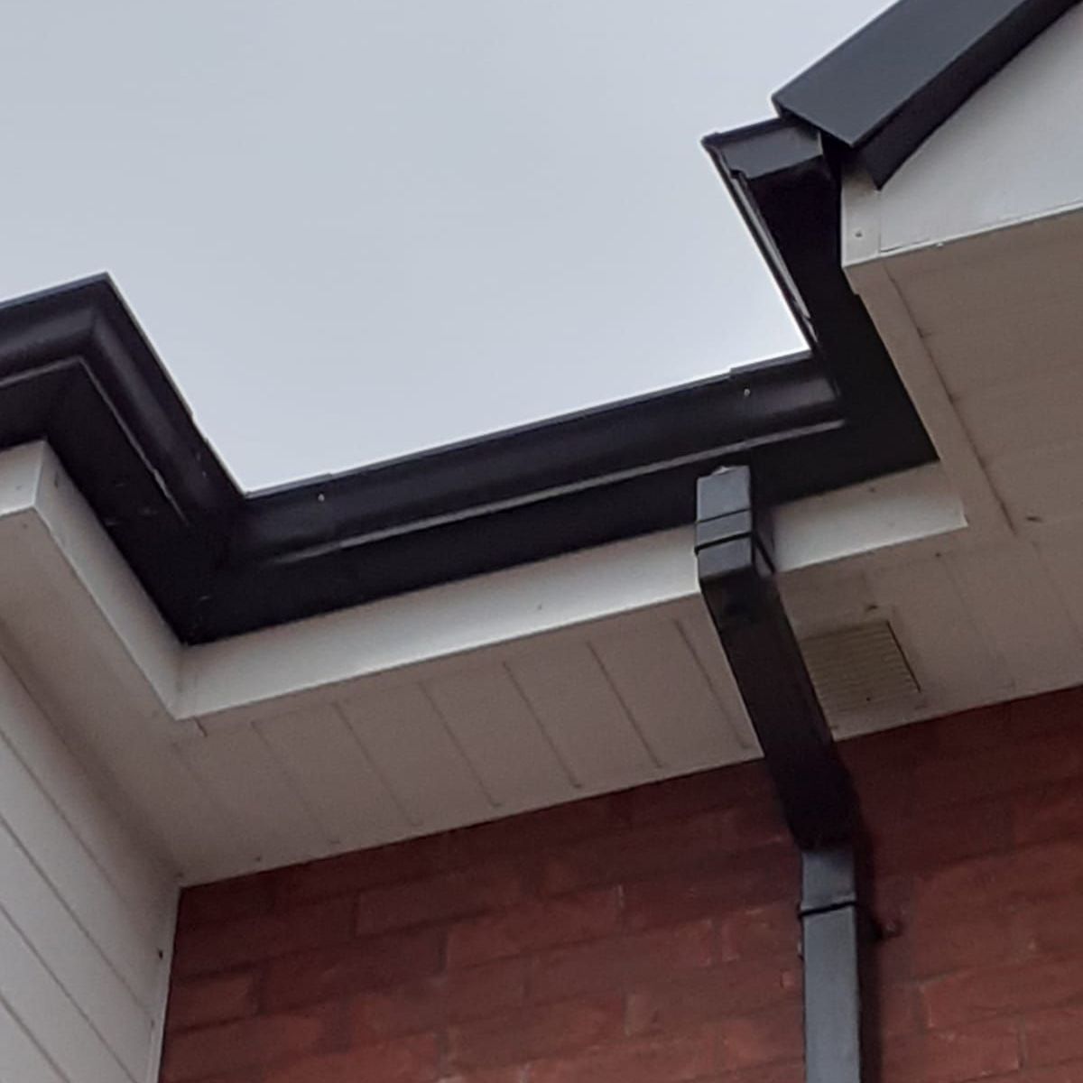 A close up of a gutter on a brick building