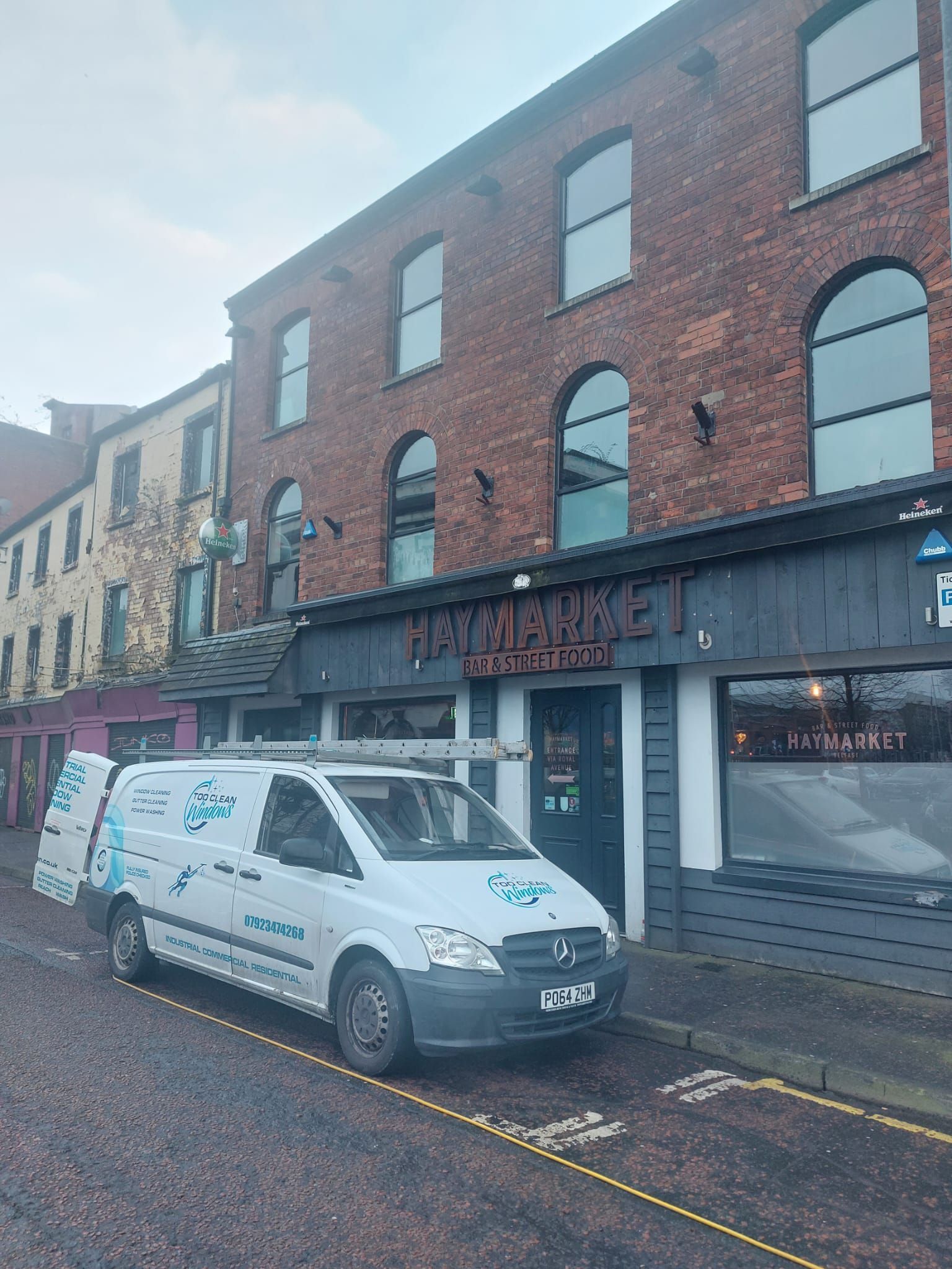 A white van is parked in front of a brick building.
