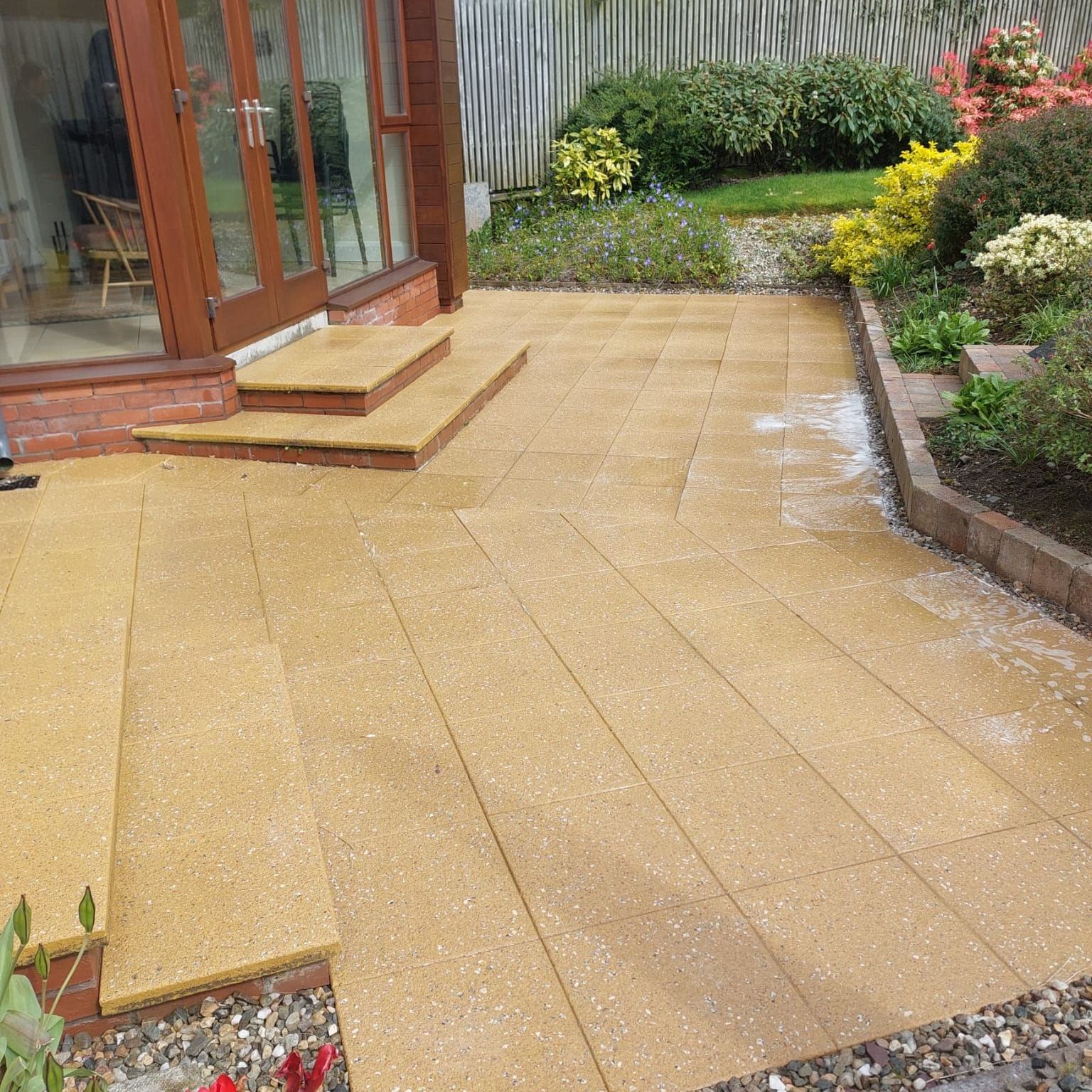 A patio with steps leading up to a house in a garden.