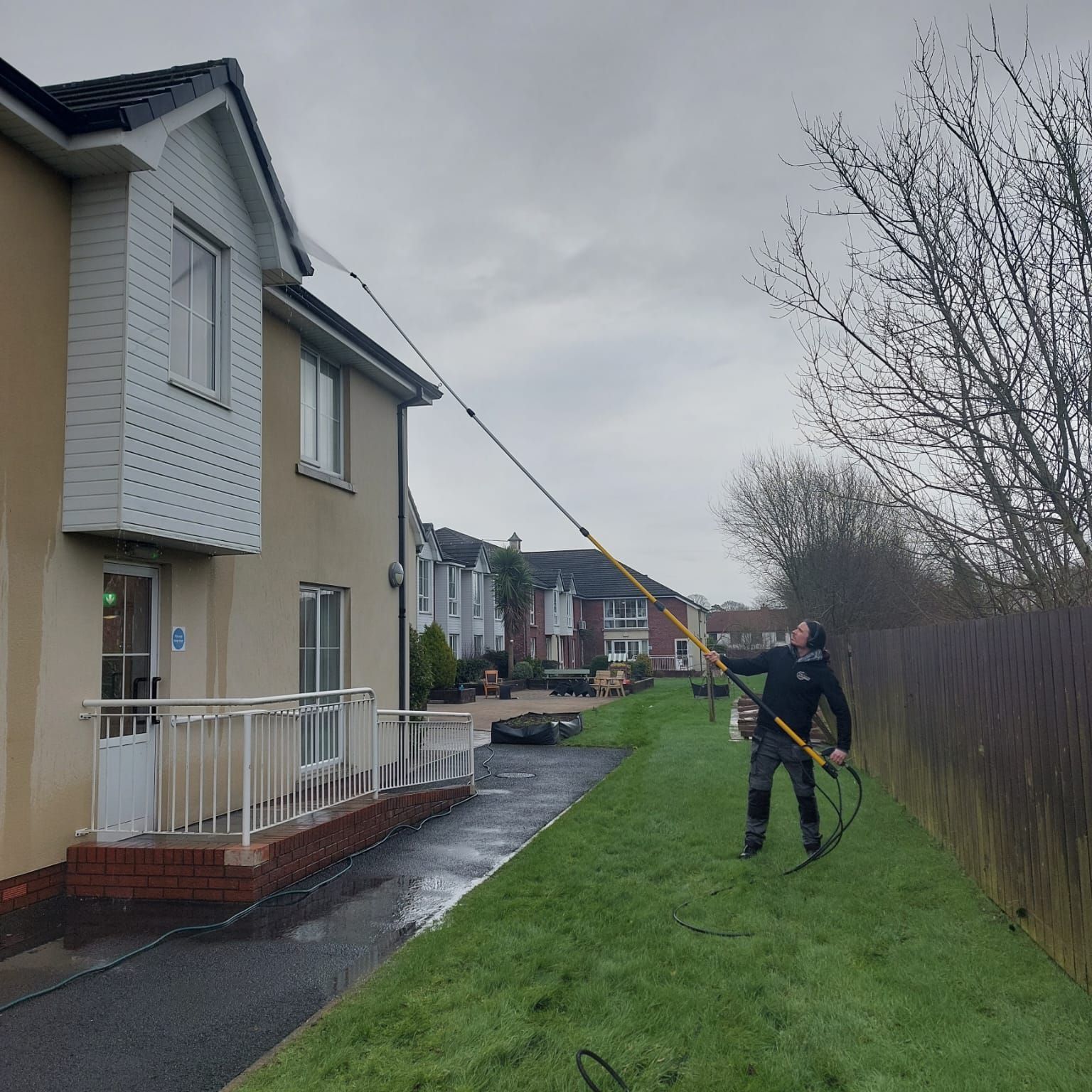 A man is cleaning a house with a hose