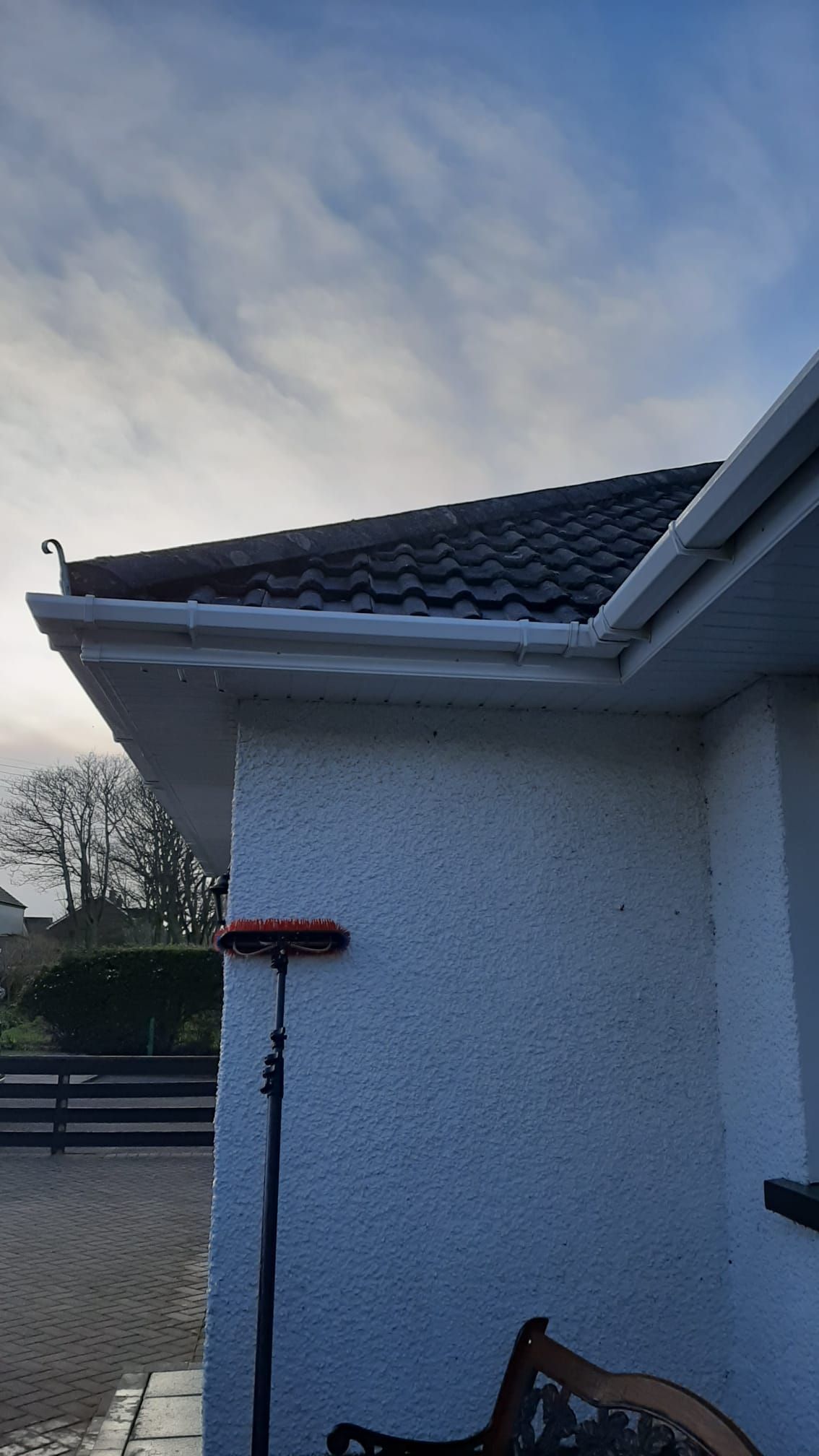 A white house with a gutter cleaner on the side of it.