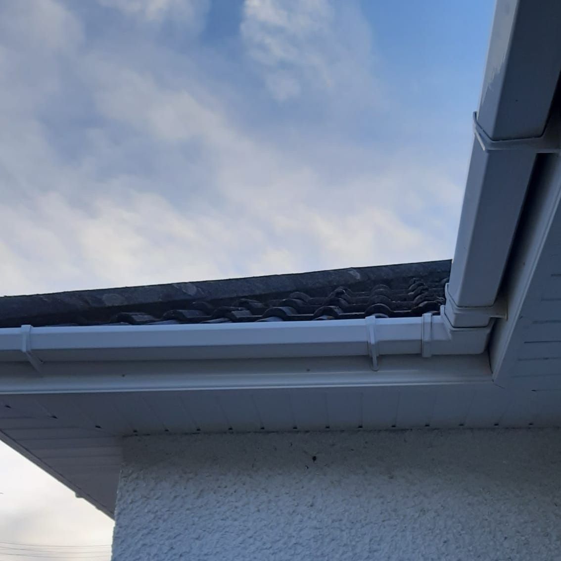 A gutter on the side of a building with a blue sky in the background.