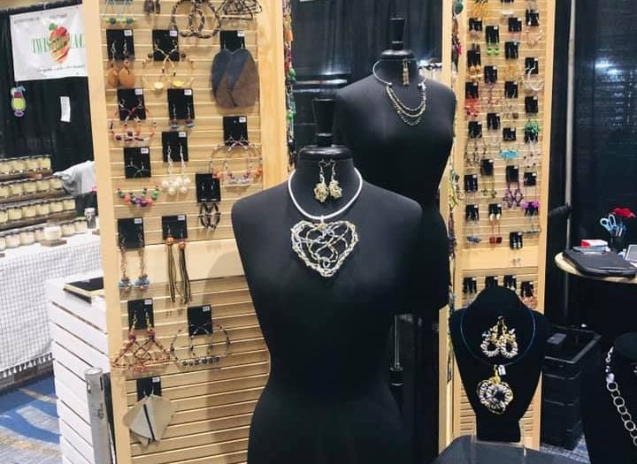 Jewelry display with mannequins wearing necklaces and earrings, wooden shelves filled with earrings.