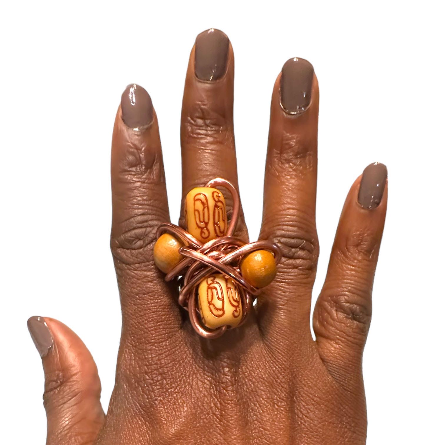 Close-up of a hand wearing a wire-wrapped ring with wooden beads and brown nail polish.